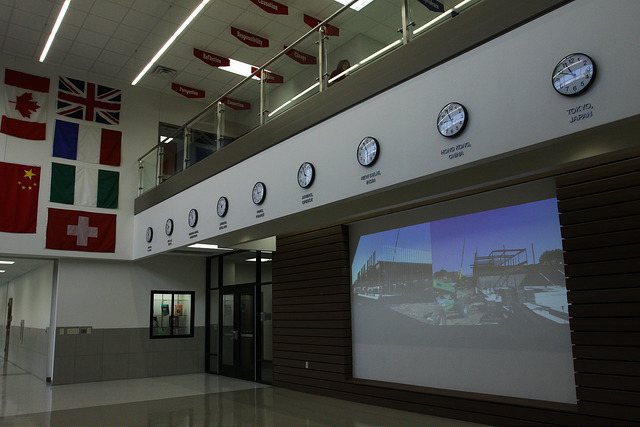 Inside entrance of Good Elementary with numerous time clocks and flags from around the world.