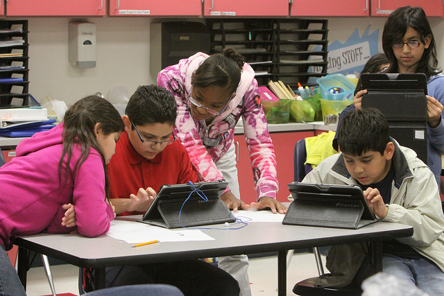 A group of 5 students playing on iPads