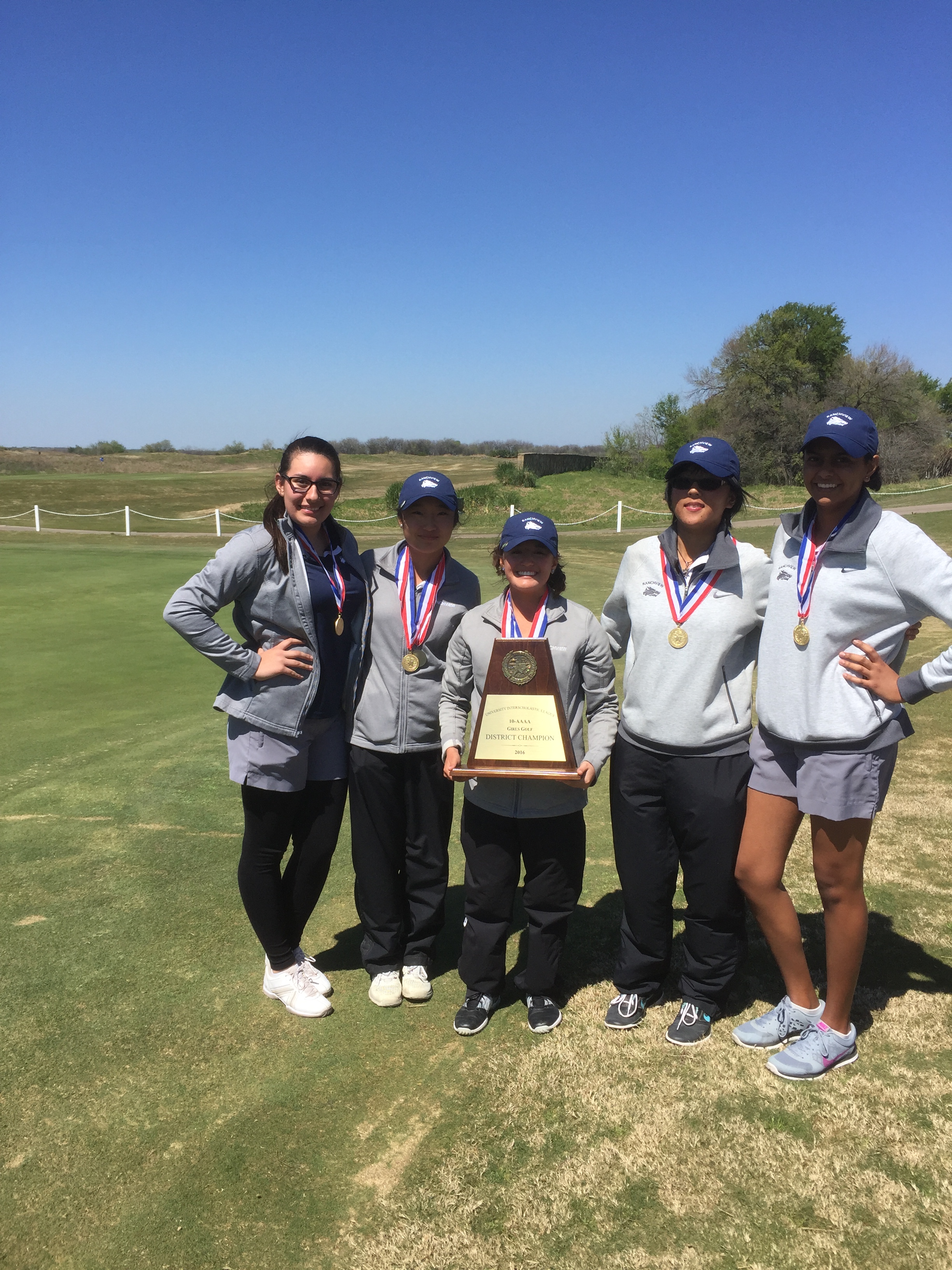 Girls Golf team with medals and holding a trophy