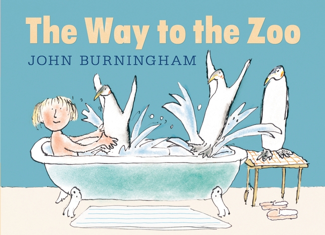 A boy sitting in a tub and penguins are splashing the water he's in while another penguin stands to the side on a small table