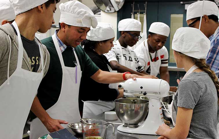 chef Nguyen Tran discusses a recipe with culinary students - Celebrity Restauranteur & Newman Smith Graduate Publishes Book