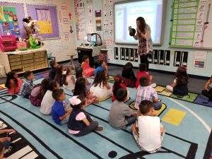 students sitting on carpet in music looking at a puppet